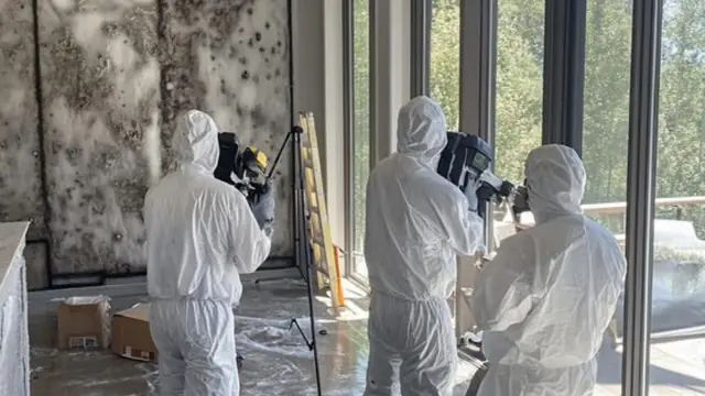 Crew in protective suits with equipment in a mold affected room